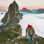Adventurous man hiking in mountains  outdoor active lifestyle travel vacations sunset Segla peak above clouds in Norway
